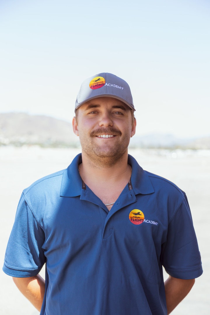 Andrew Zioncheck, instructor, smiling outdoors in branded attire.