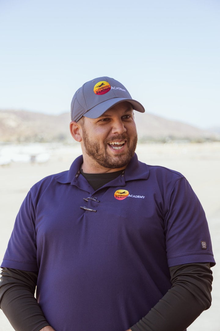 Curtis Beezely, instructor, smiling outdoors in a blue uniform.