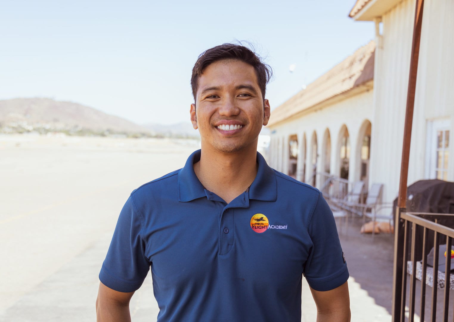 Francis Dulay, Instructor, smiling outdoors near a building.
