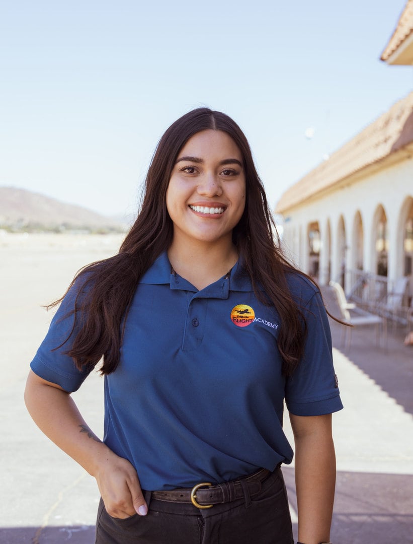 Pazeanna Santos, instructor, smiling outdoors near a tiled-roof building.