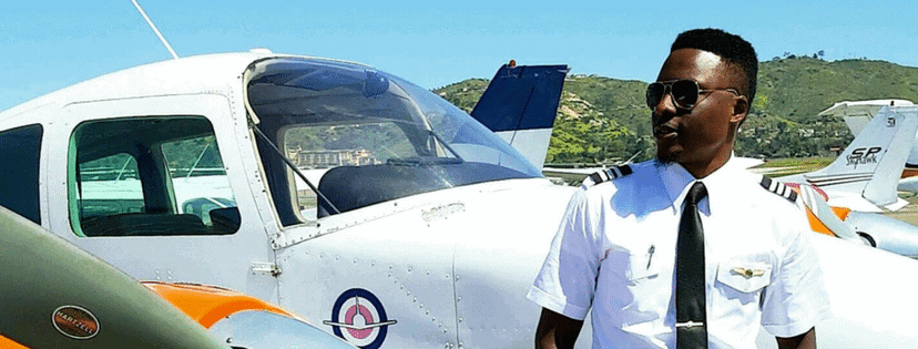 Pilot in uniform standing beside a small aircraft, sunny San Diego day.