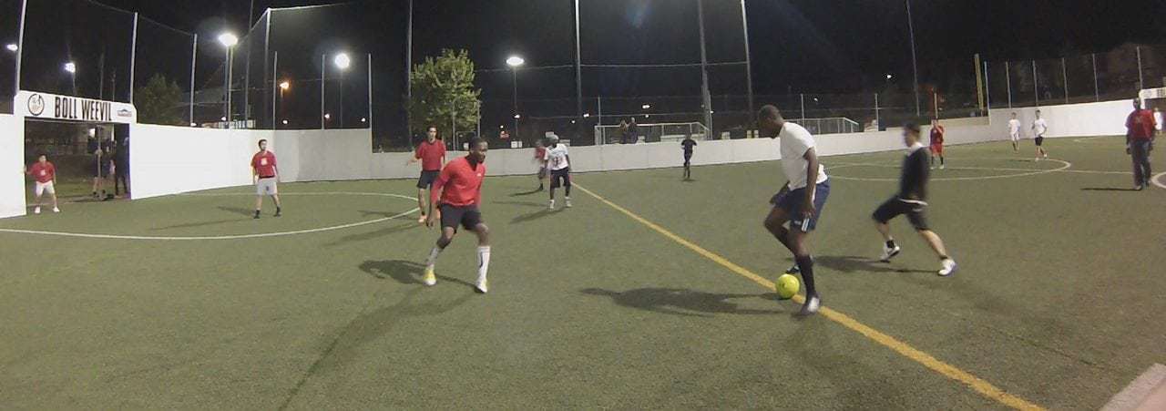 People playing soccer at night on a lit San Diego field.