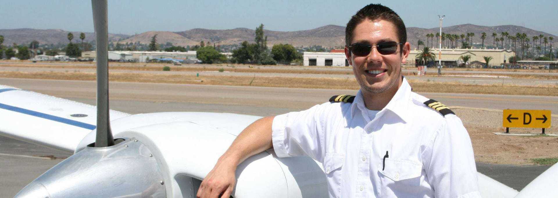 Pilot standing by a small aircraft on a sunny day in San Diego.